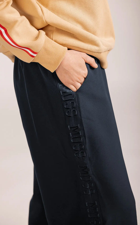 Person wearing a beige sweater and black pants with text on a light pink background