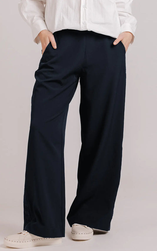 Person wearing navy wide-leg pants with a plain background