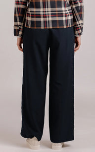 Person wearing black wide-leg pants with a plaid shirt on a plain background