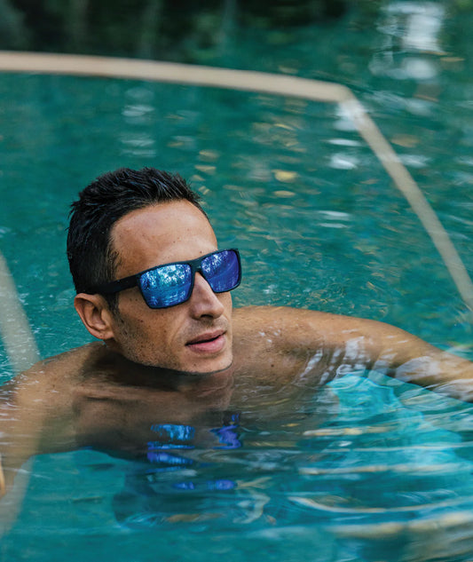 Man wearing sunglasses swimming in a pool
