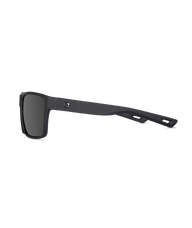 Matte black square sunglasses with dark lenses and a small white logo on the temple, shown from a side profile on a white background.