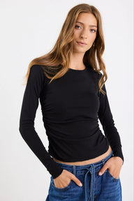 Woman wearing a black long-sleeve top and blue jeans on a white background