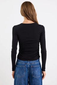 Person wearing a black long-sleeve top and blue jeans on a white background
