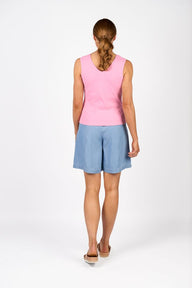 Woman wearing a pink sleeveless top and light blue shorts on a white background