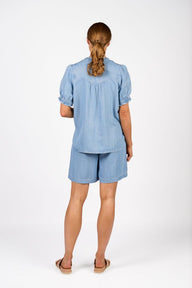 Woman wearing a light blue outfit with shorts on a white background