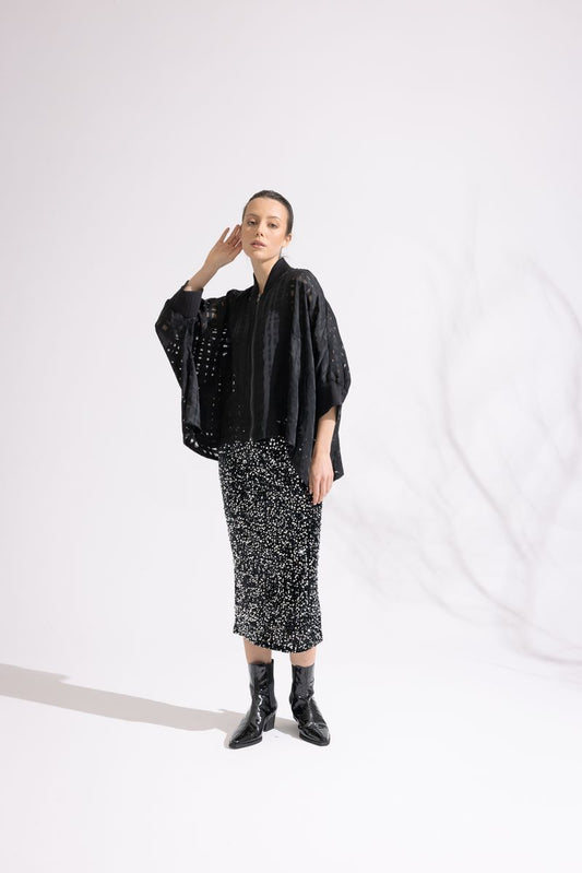 Person wearing a black outfit with a patterned skirt on a white background