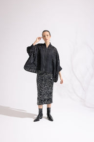 Person wearing a black outfit with a patterned skirt on a white background