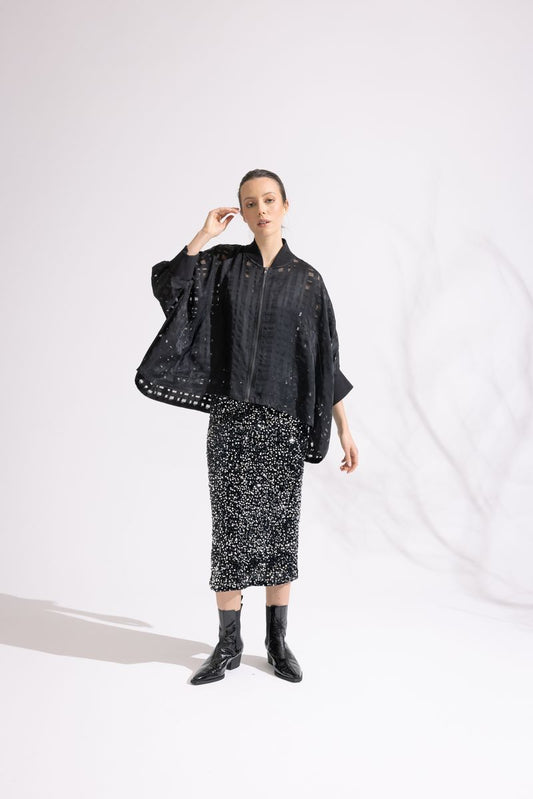 Person wearing a black outfit with a patterned skirt on a white background