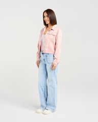 Woman wearing a pink denim jacket and light blue jeans on a white background
