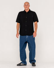 Man wearing a black shirt and blue jeans on a white background