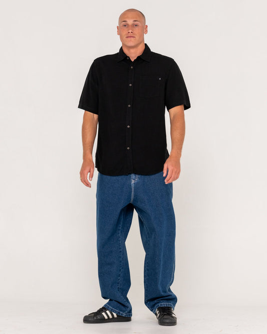 Man wearing a black shirt and blue jeans on a white background