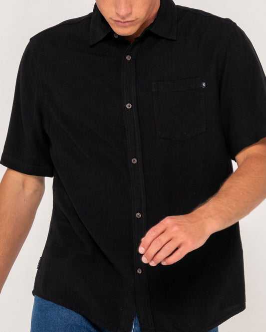 Man wearing a black short-sleeve button-up shirt on a white background