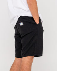 Person wearing black shorts with a logo on a white background
