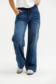 Person wearing blue wide-leg jeans on a white background
