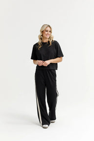 Woman wearing a black outfit with white stripes on a white background
