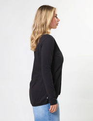 Woman wearing a black long-sleeve shirt and blue jeans on a white background