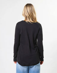 Person wearing a black long-sleeve top with a plain background