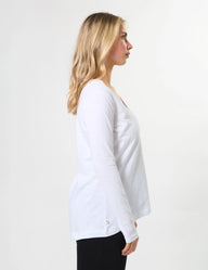 Woman wearing a white long-sleeve top against a plain background