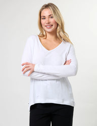 Woman wearing a white long-sleeve shirt against a plain background
