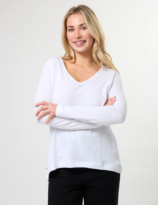 Woman wearing a white long-sleeve shirt against a plain background