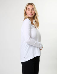 Woman wearing a white long-sleeve top against a plain background