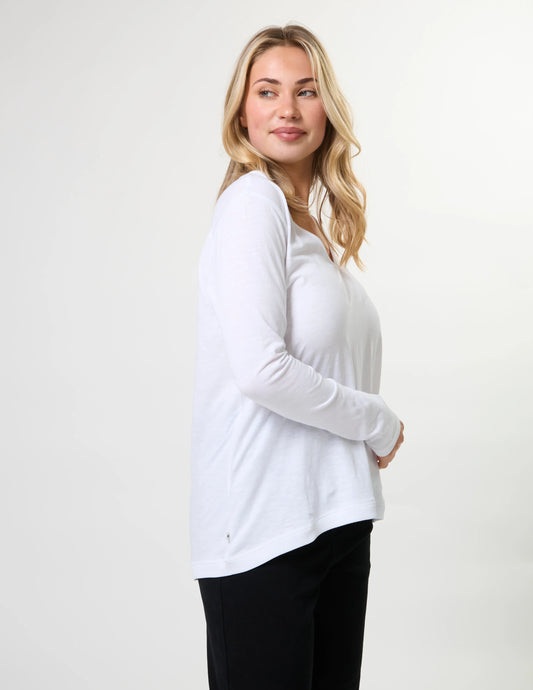 Woman wearing a white long-sleeve top against a plain background