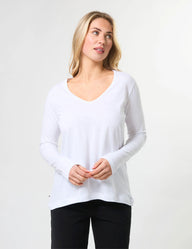 Woman wearing a white long-sleeve shirt against a plain background