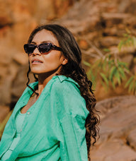 Woman wearing sunglasses and a green shirt in a natural setting