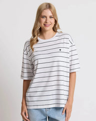 Woman wearing a white t-shirt with black stripes on a plain background