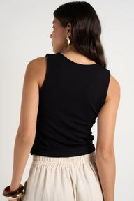 Woman wearing a black sleeveless top and beige pants on a white background