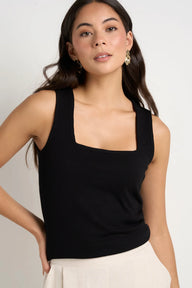 Woman wearing a black sleeveless top against a plain background