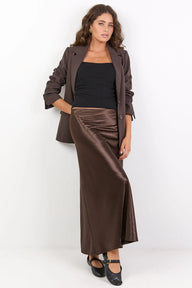 Woman wearing a brown jacket and satin skirt on a white background