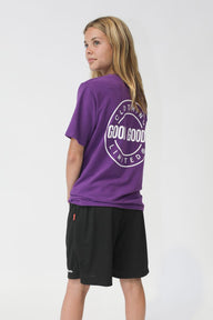 Person wearing a purple t-shirt with a logo on the back, standing against a white background