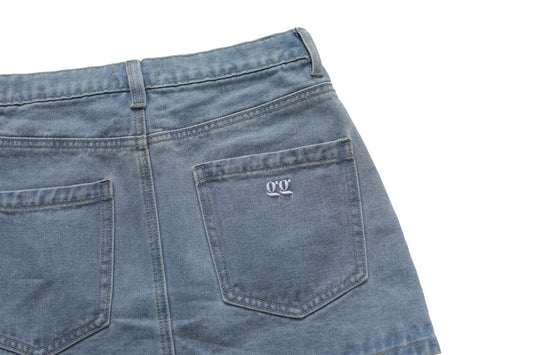 Close-up of blue denim skirt with a brand logo on a white background