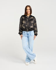 Woman wearing a black floral blouse and light blue jeans on a white background