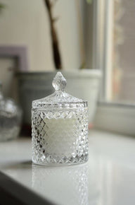 Decorative glass jar with a textured lid on a reflective surface