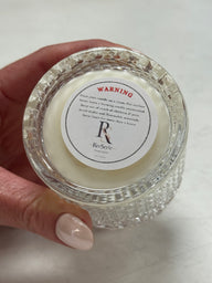 Candle in a decorative glass holder with a warning label on a white background