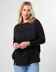 Woman wearing a black top and blue jeans on a white background