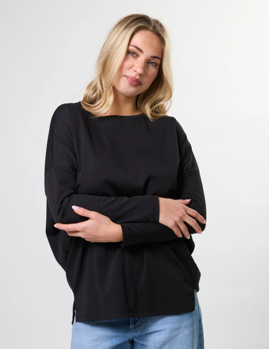 Woman wearing a black top and blue jeans against a white background