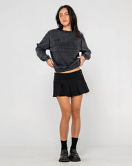 Woman wearing a dark gray sweatshirt and black pleated skirt on a white background