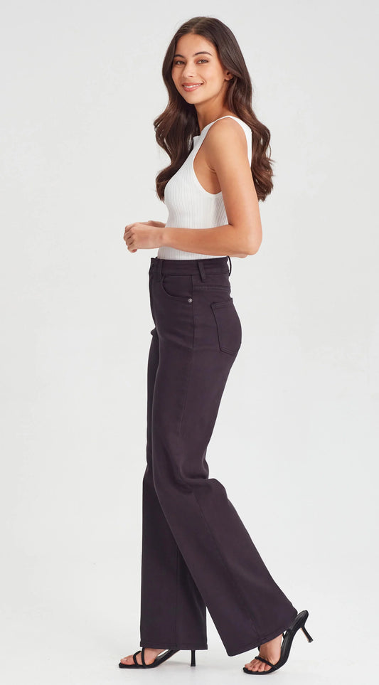 Woman wearing a white sleeveless top and dark high-waisted pants on a white background
