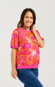 Woman wearing a colorful floral top and blue jeans on a white background
