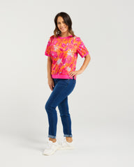 Woman wearing a colorful floral shirt and blue jeans on a white background