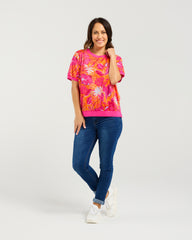 Woman wearing a colorful floral shirt and blue jeans on a white background