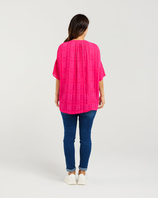 Person wearing a bright pink top and blue jeans on a white background