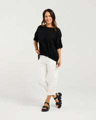 Lady in Black Nikita Top with White 3/4 pants and a white background