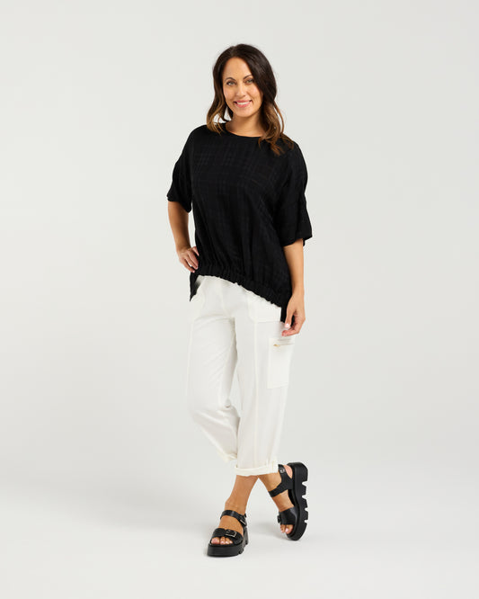 Lady in Black Nikita Top with White 3/4 pants and a white background
