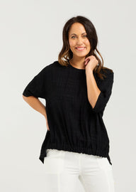 Lady in Black Nikita Top with White 3/4 pants and a white background