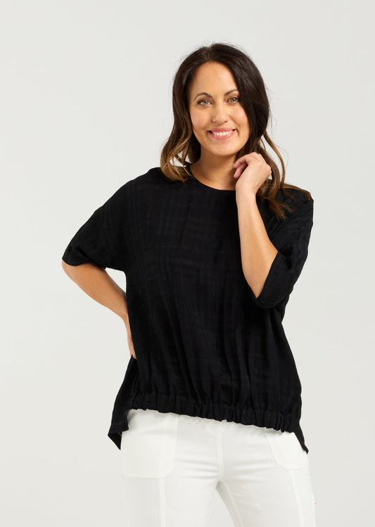 Lady in Black Nikita Top with White 3/4 pants and a white background