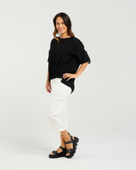 Lady in Black Nikita Top with White 3/4 pants and a white background